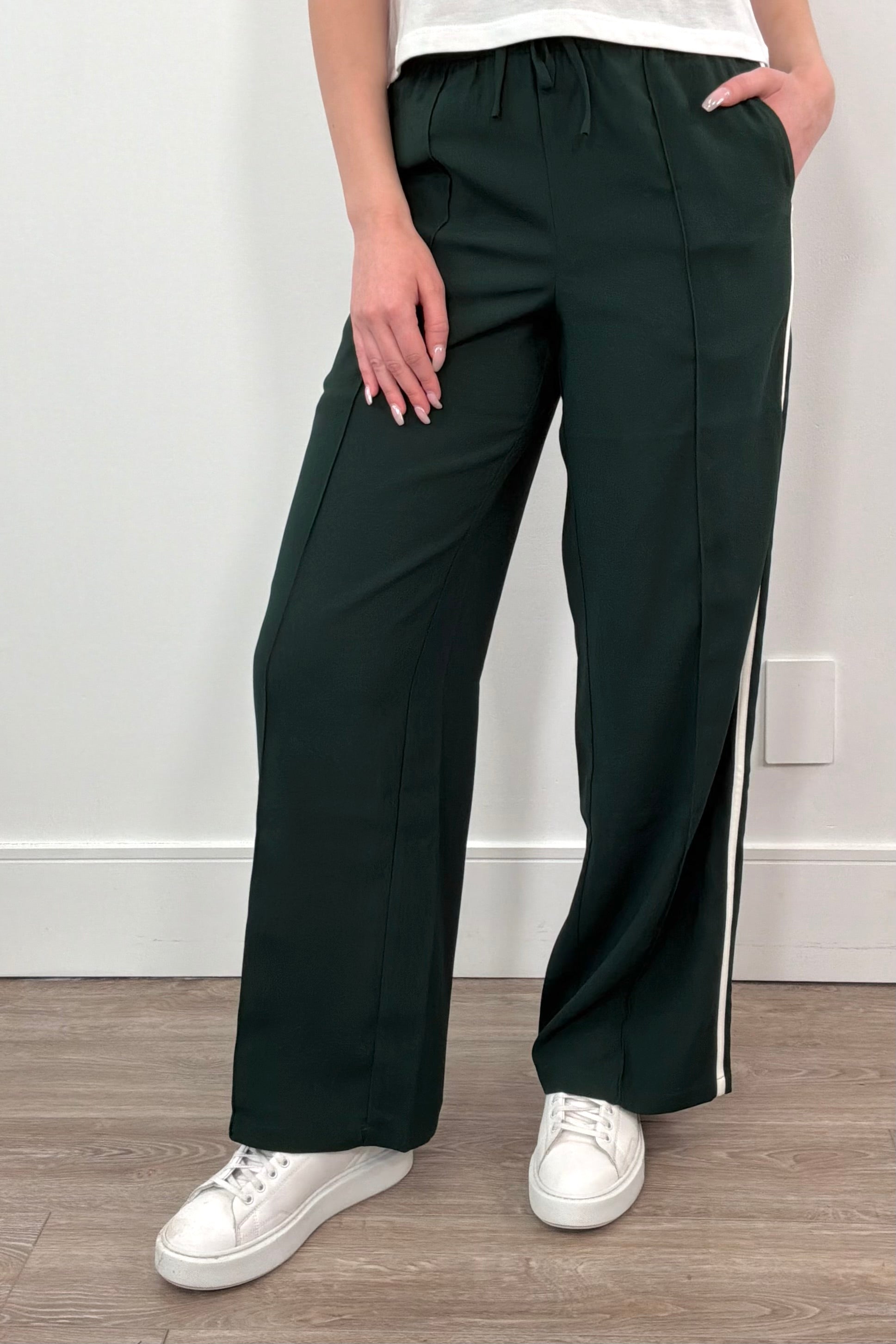 woman wearing a green track pant with white stripes down its side