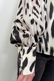 Close up view of the cuff woman wearing a sheer printed blouse with a cami underneath