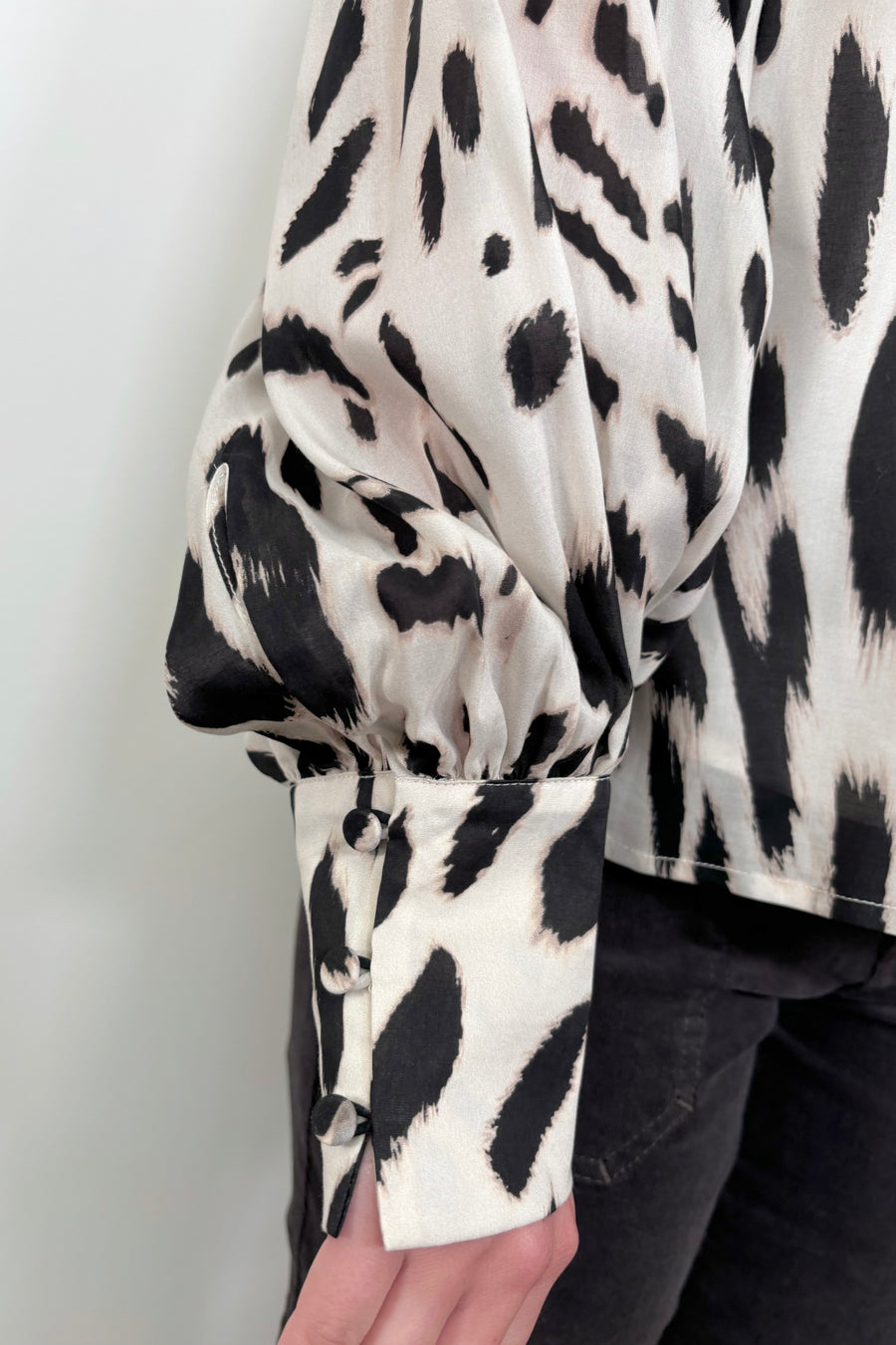 Close up view of the cuff woman wearing a sheer printed blouse with a cami underneath