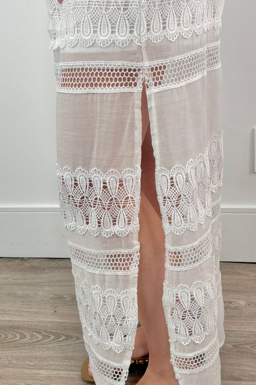 Side close-up of a maxi strapless white dress with lace details in the skirt