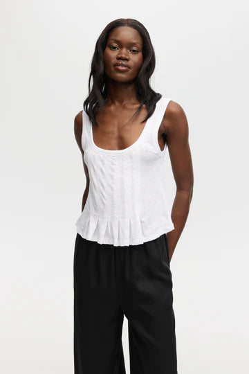 Woman wearing a white tank top with a ruffled bottom seam