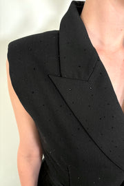 Close up of woman’s left shoulder wearing a black pinstriped jumpsuit with sparkle embelishment