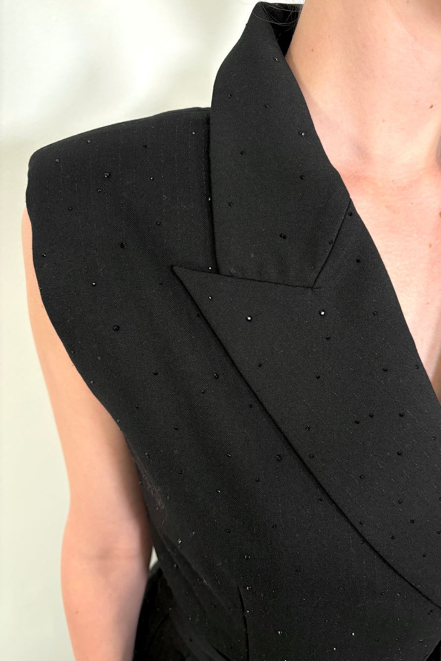 Close up of woman’s left shoulder wearing a black pinstriped jumpsuit with sparkle embelishment