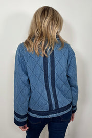 Back facing woman wearing a blue quilted jacket with navy blue detailing.