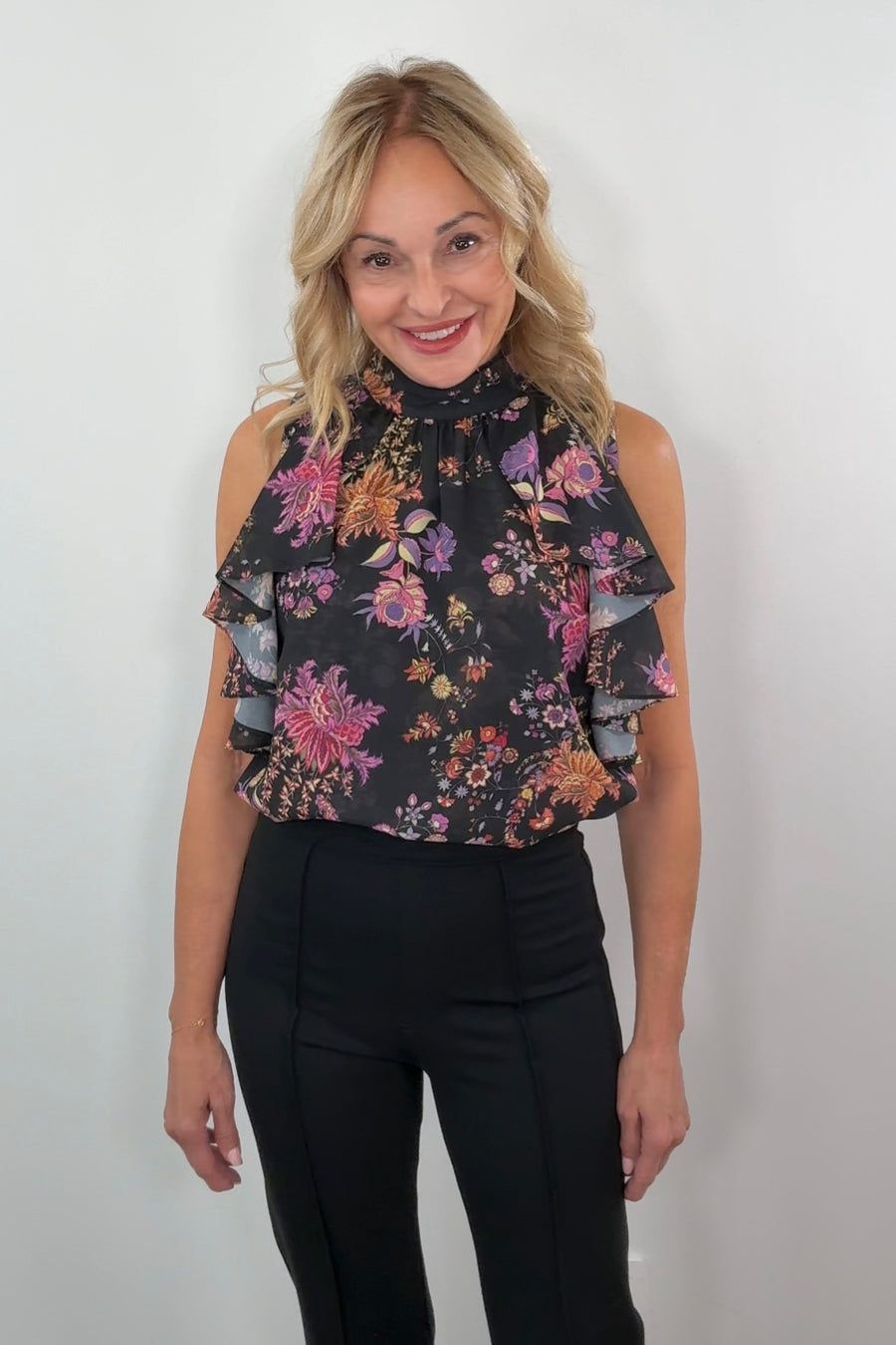 woman wearing a black sleeveless flower patterned ruffle top