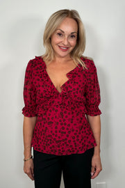 Front view of woman wearing a cool red chiffon top with a daisy pattern
