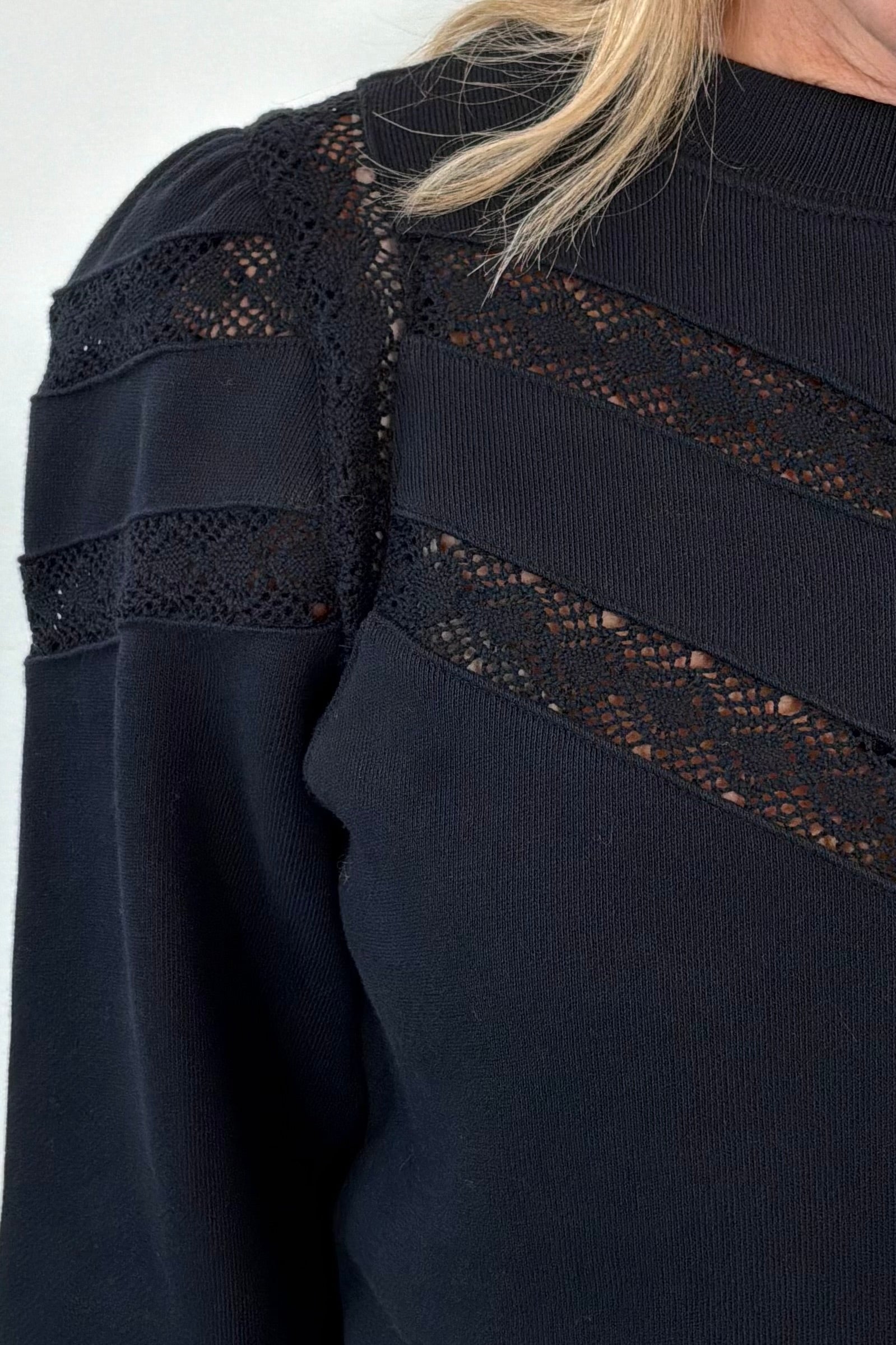 close-up of a black sweatshirt with lace detailing and cuffed poplin  sleeves