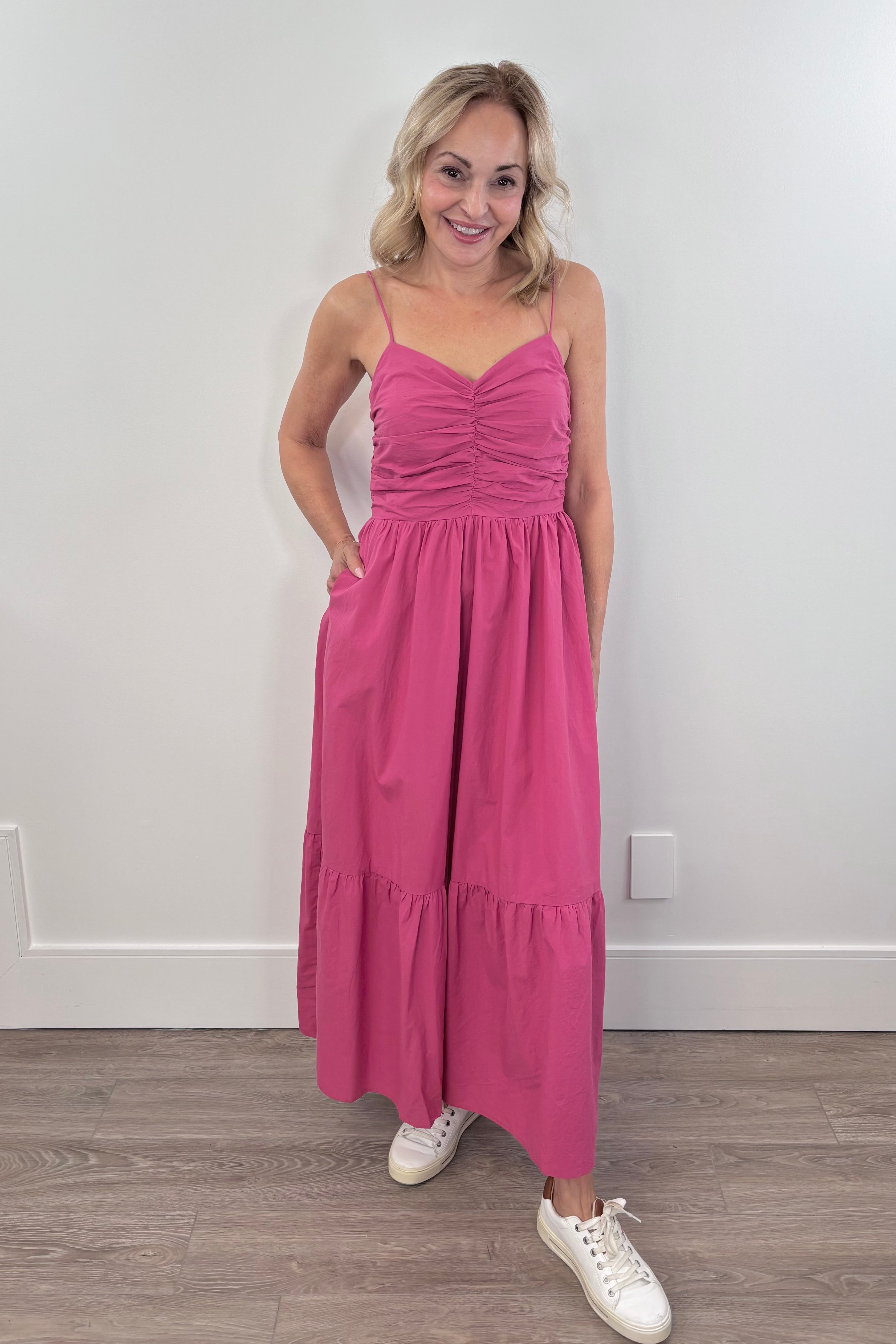 Woman wearing a dark pink midi dress with a ruffled chest