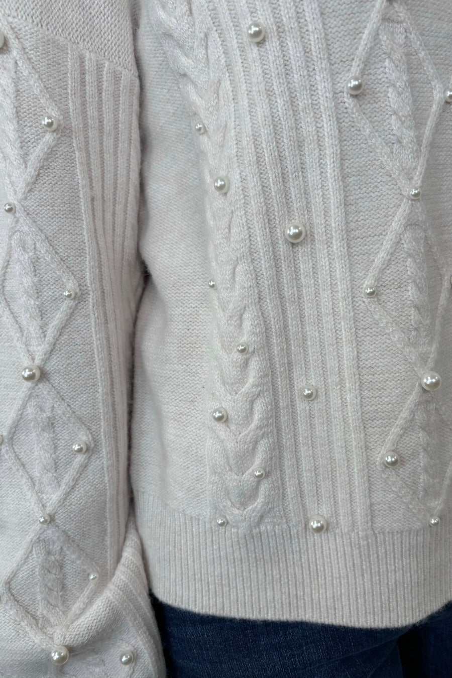 Close-up of a white sweater with pearl embellishments 