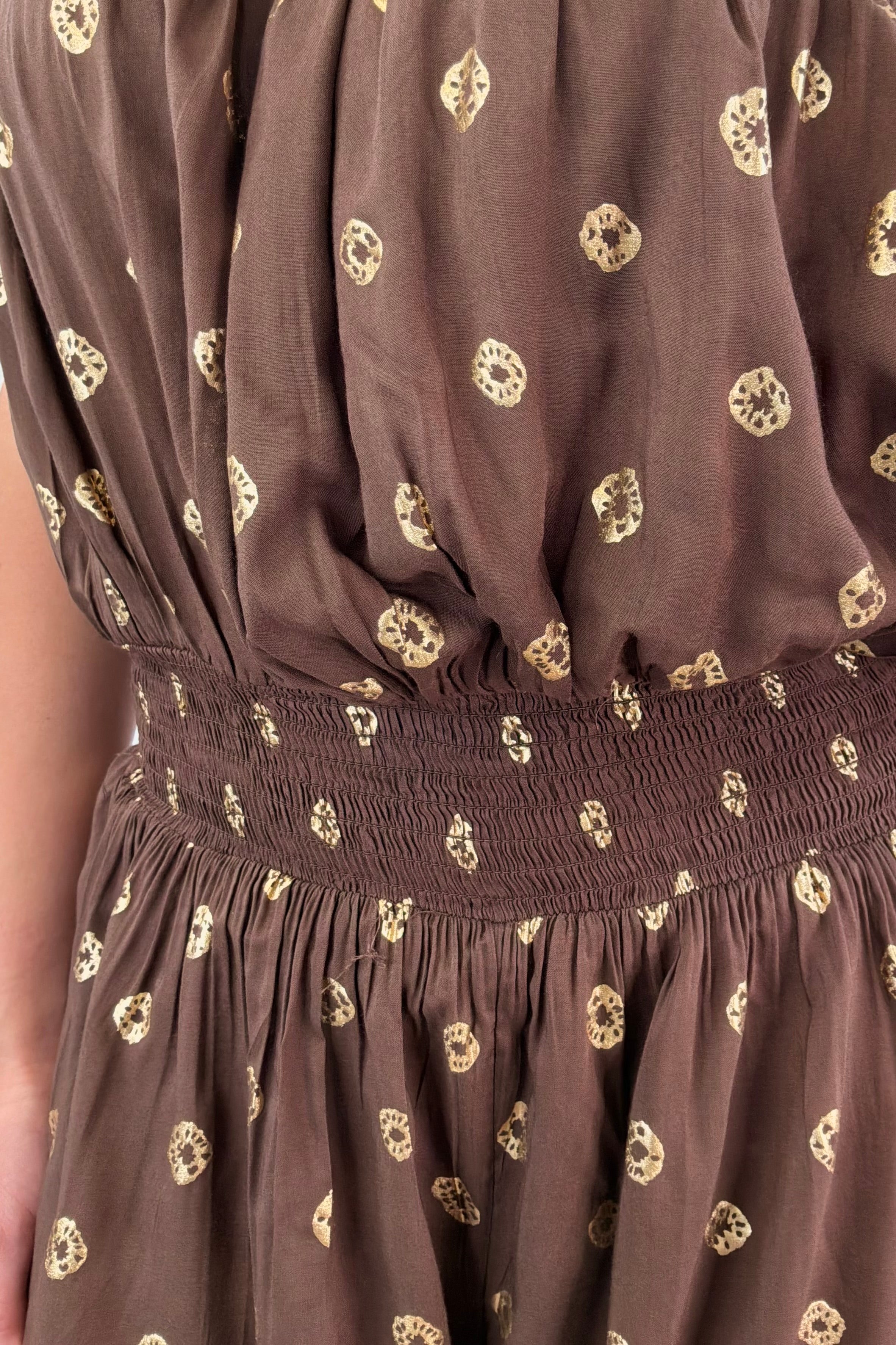 Close up of woman in brown strapless romper with polka dot detail