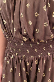 Close up of woman in brown strapless romper with polka dot detail