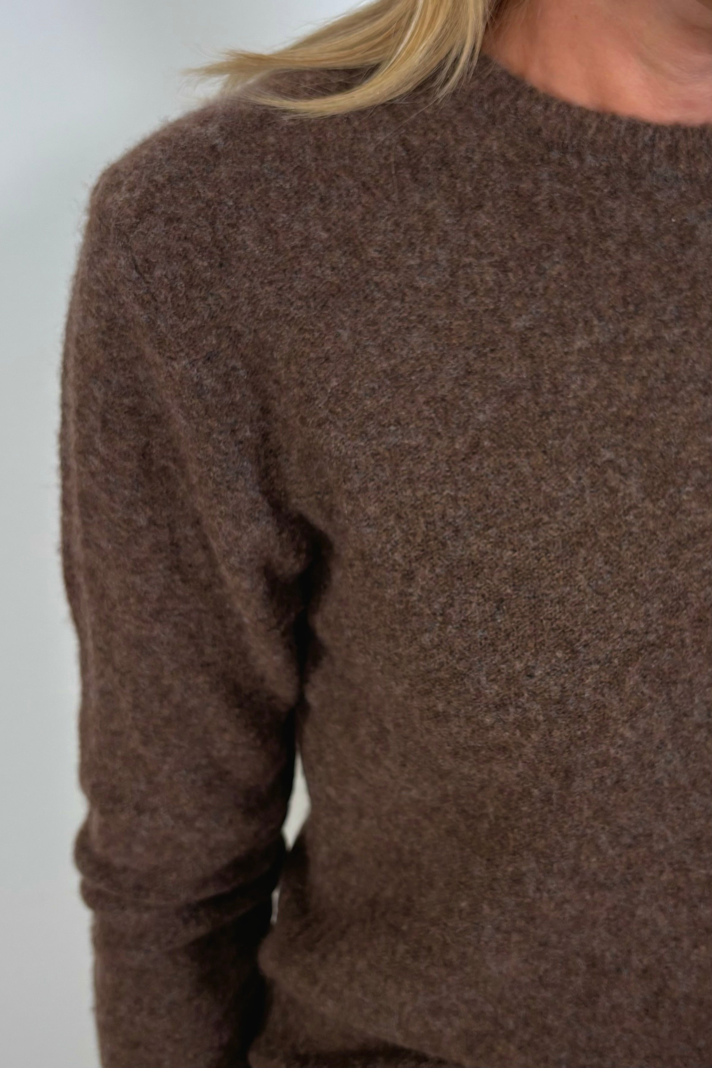 Shoulder close-up of a woman wearing a lightweight brown sweater
