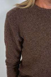 Shoulder close-up of a woman wearing a lightweight brown sweater