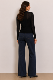 Woman wearing a black long-sleeve knit top. 