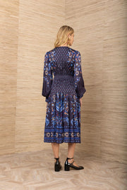 ack view of woman wearing a patterned navy blue long sleeve midi dress