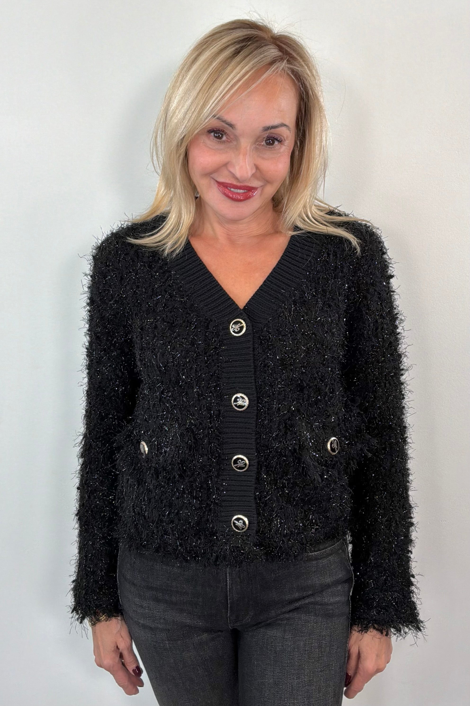 Woman wearing a black textured cardigan with gold buttons 