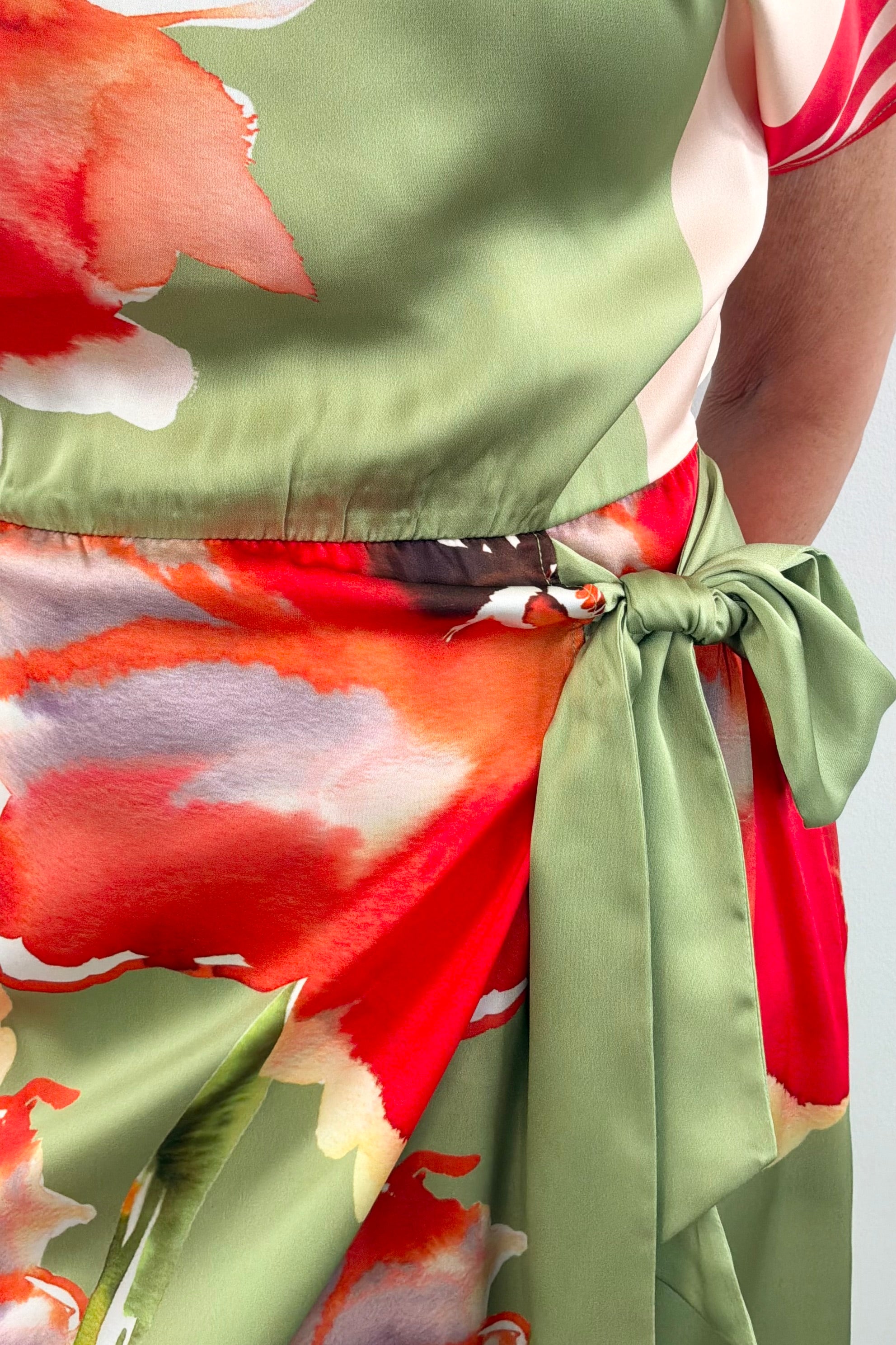 Woman wearing a boat neck short sleeve wrap waist scarf colorful floral dress