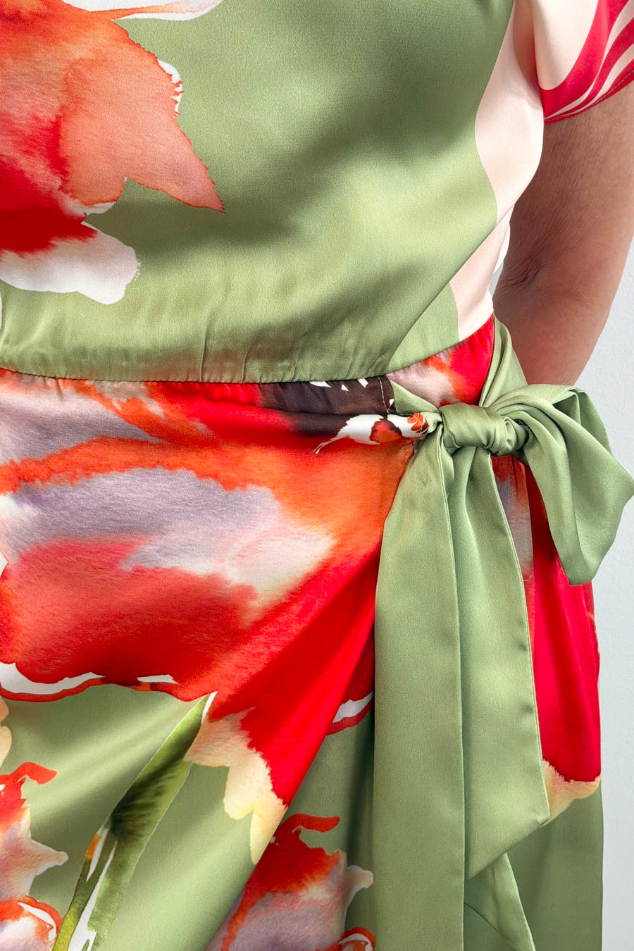 Woman wearing a boat neck short sleeve wrap waist scarf colorful floral dress