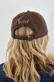 Women wearing a brown cap with a light blue heart patch