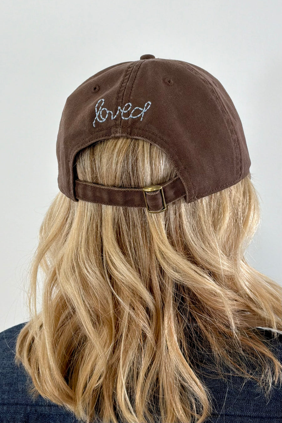 Women wearing a brown cap with a light blue heart patch