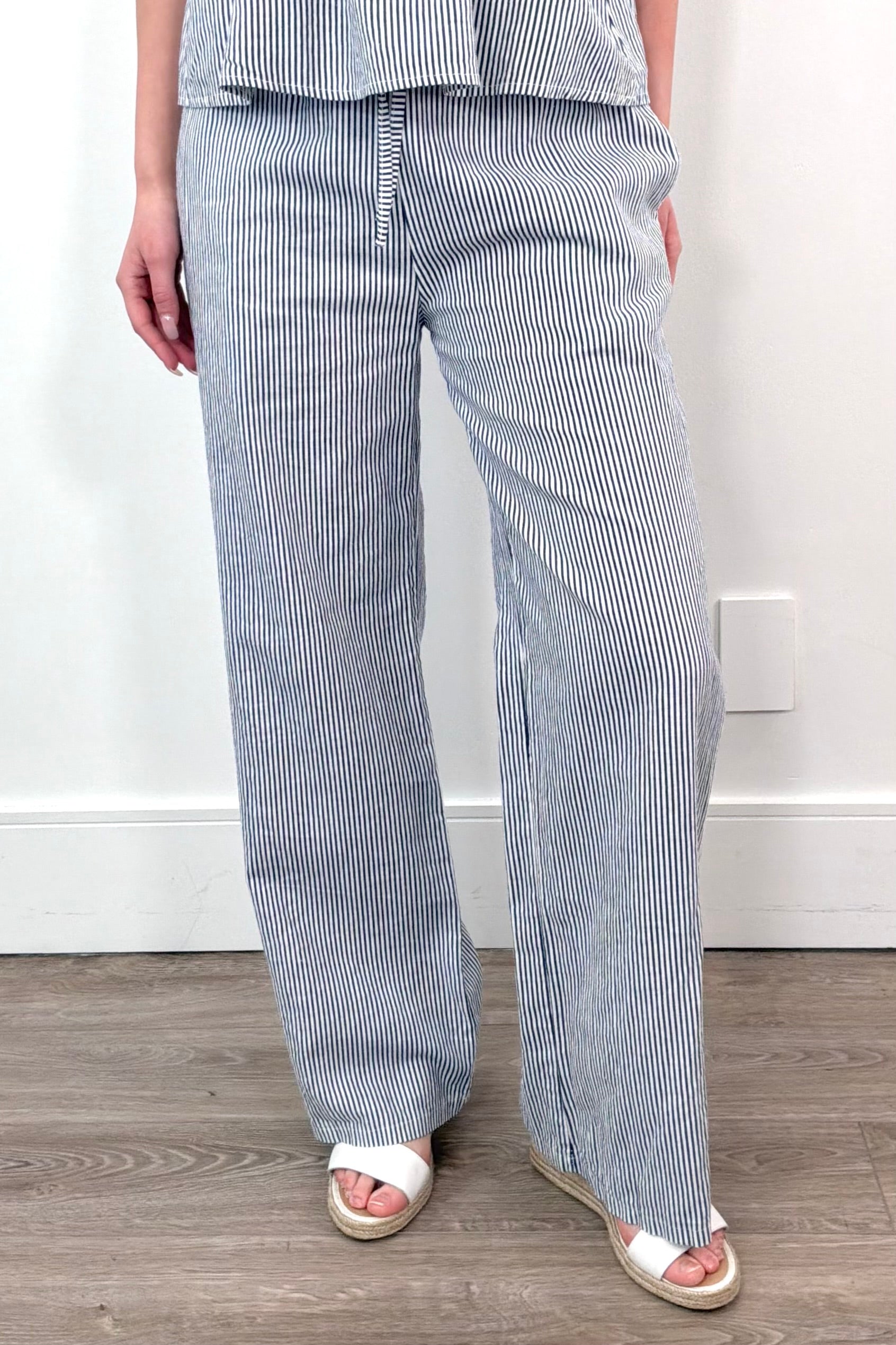 A woman wearing a light blue and white striped wide leg pant with a drawstring waist