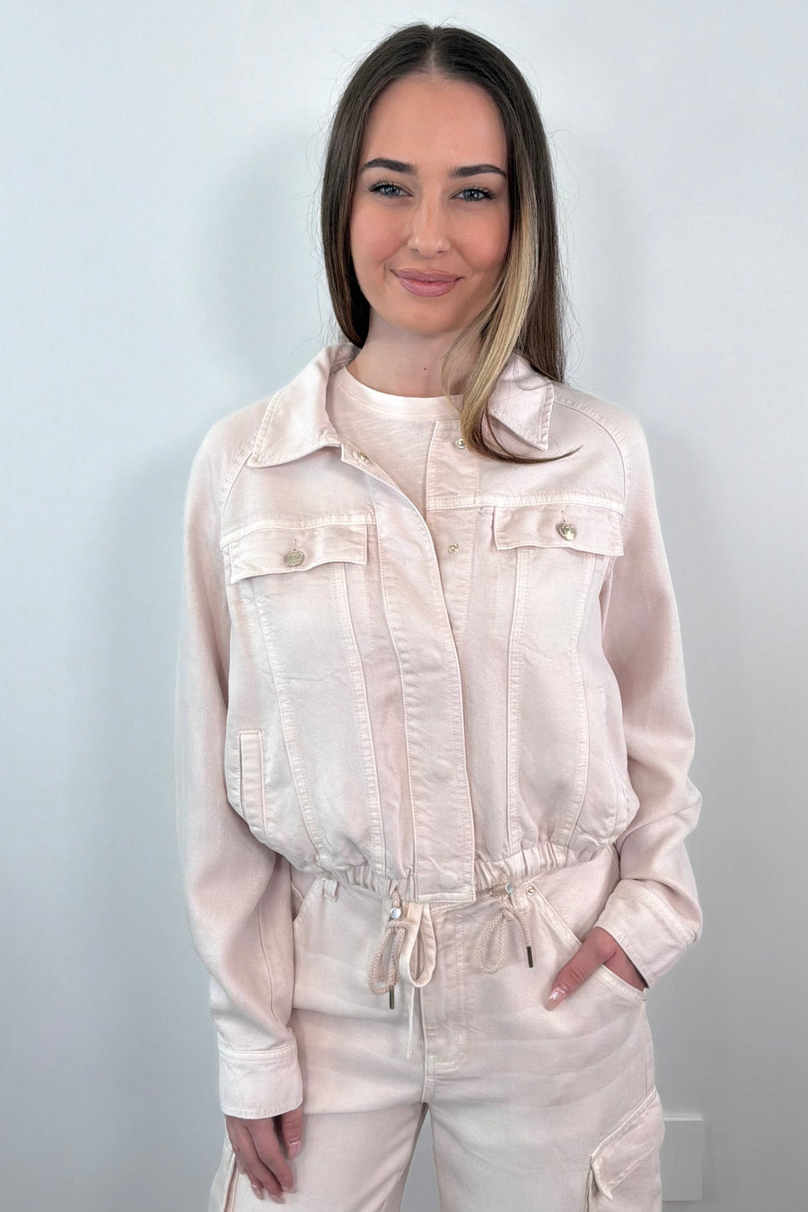 woman wearing a buttoned up light pink denim jacket 