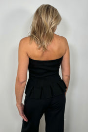Back view of woman wearing a black pleaded at the bottom strapless top 