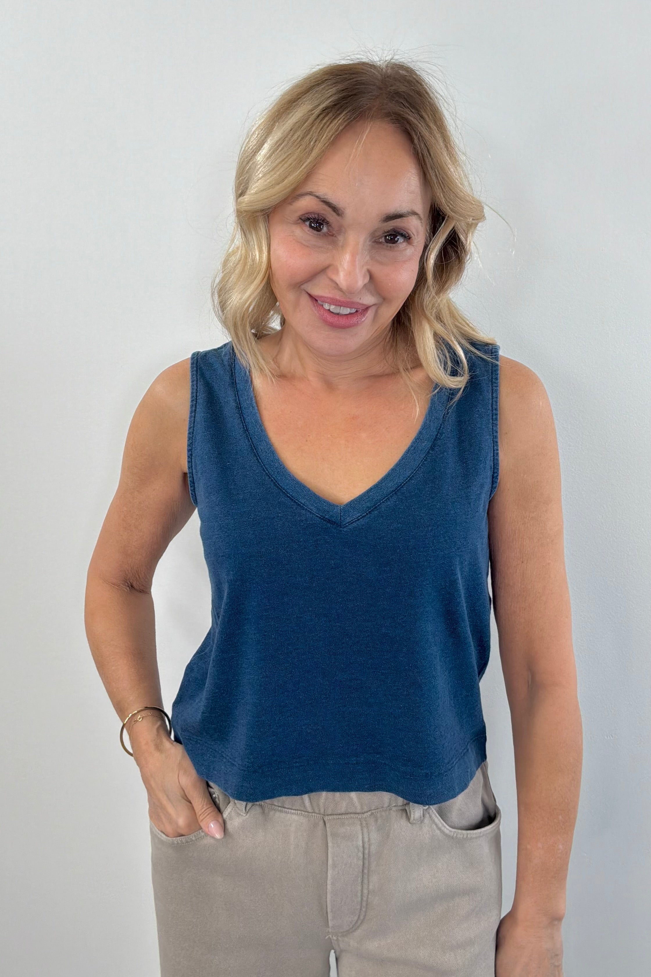 Woman wearing a navy blue denim wash sleeveless v-neck knit tank top with relaxed fit
