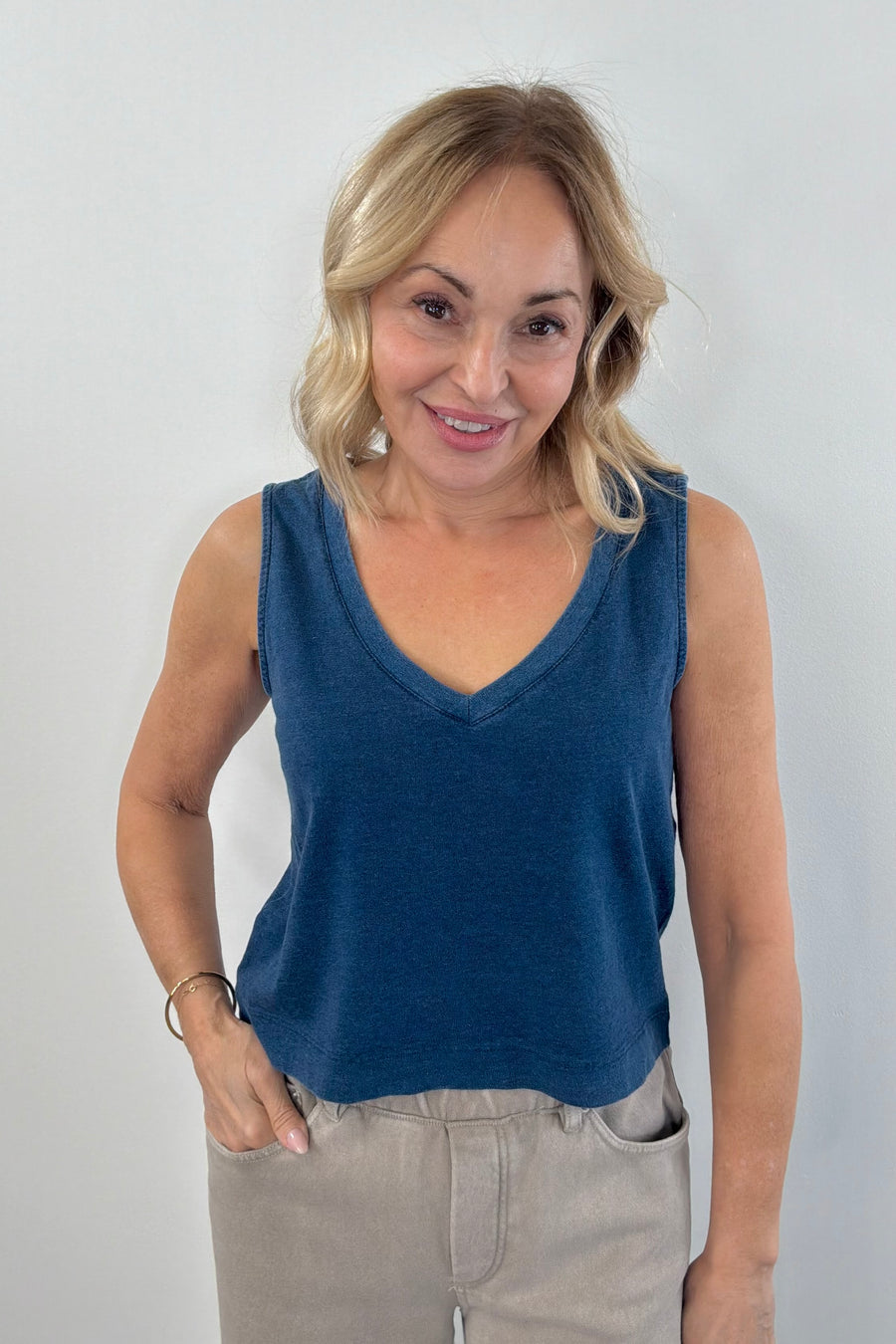 Woman wearing a navy blue denim wash sleeveless v-neck knit tank top with relaxed fit