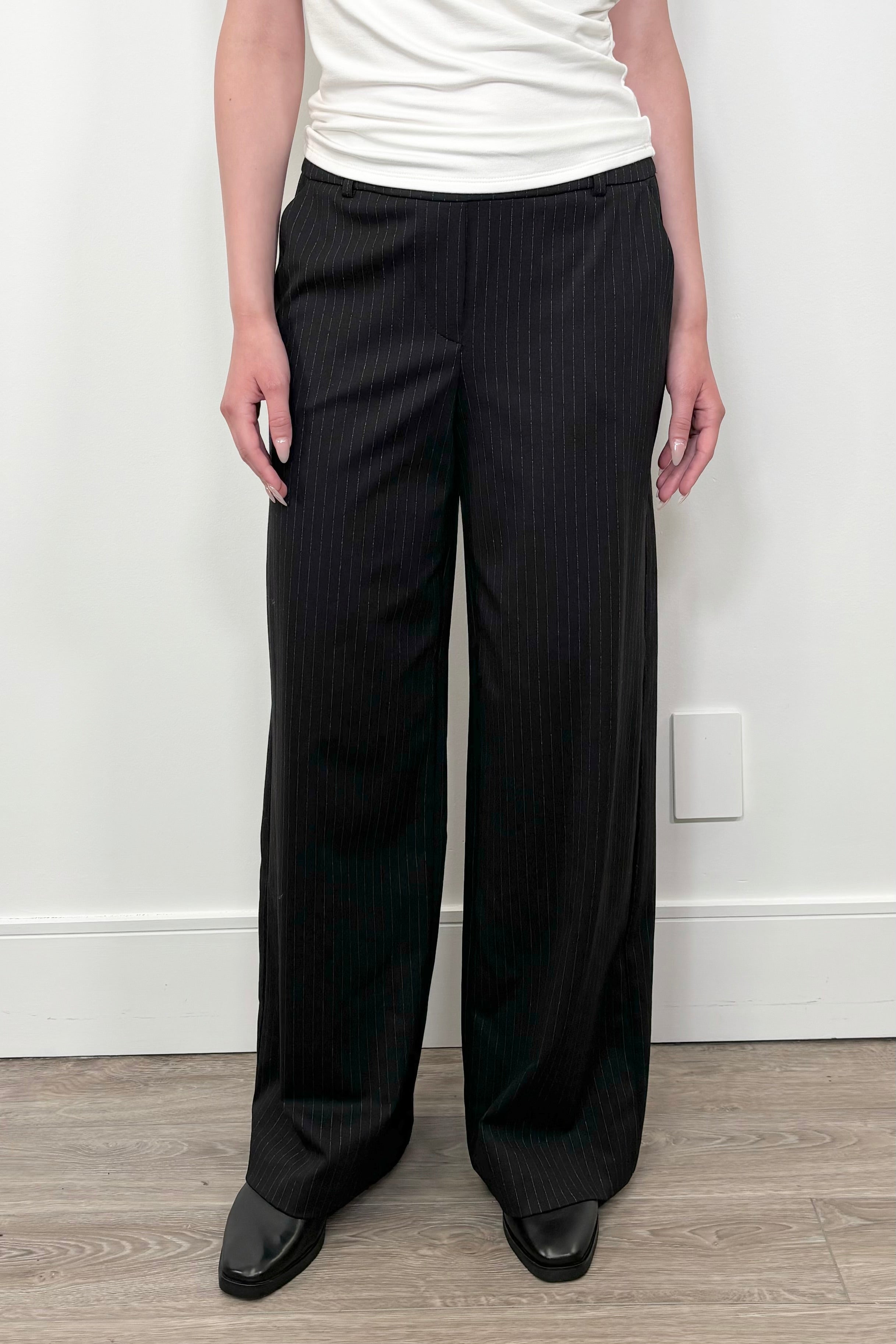 Front facing woman wearing black pinstriped ponte pants