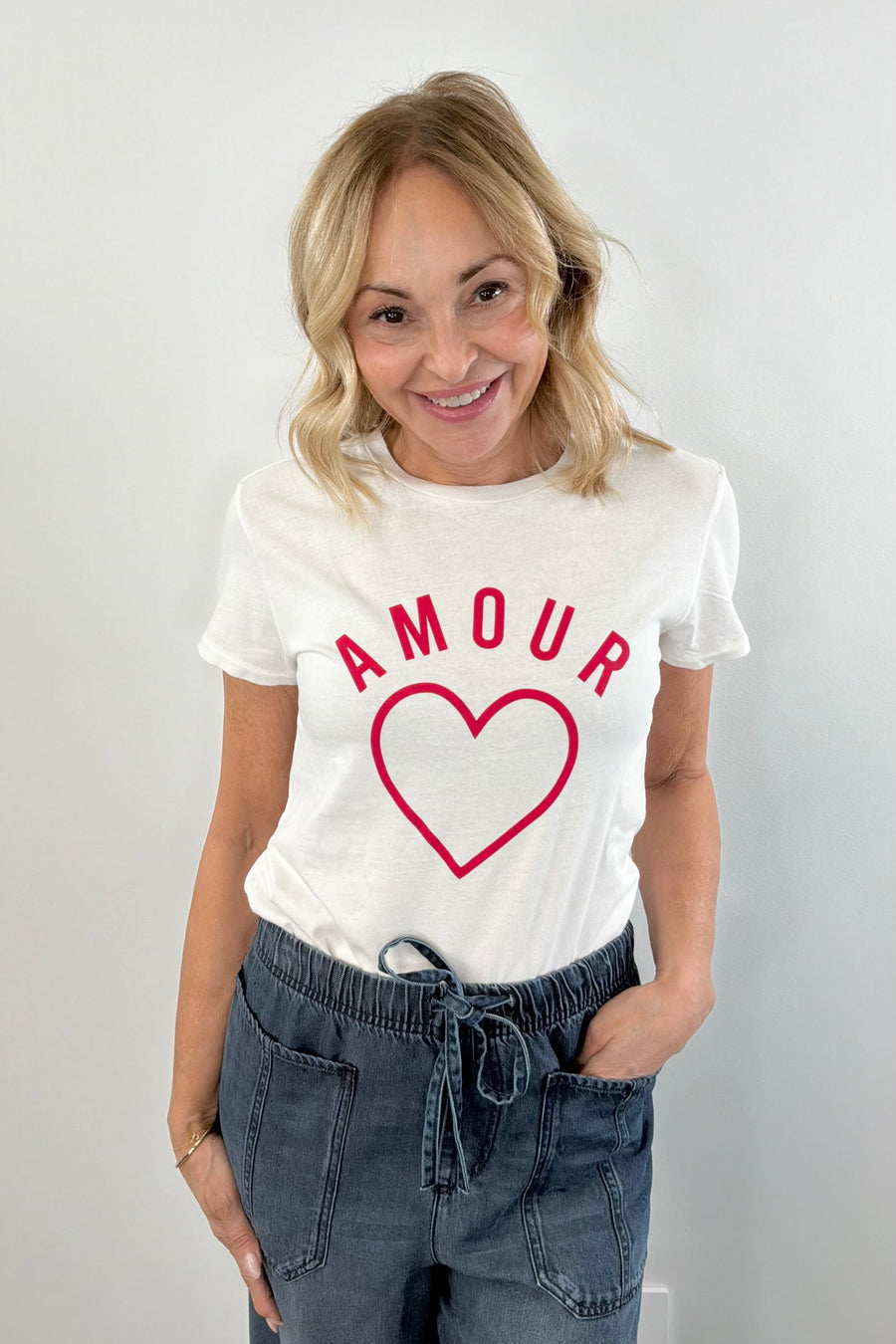 Woman wearing a white crewneck t-shirt with the word "AMOUR" written in red lettering