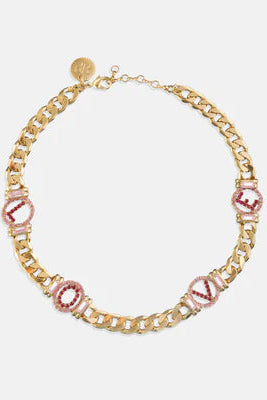 Gold chain necklace with pink gemstones on a white background
