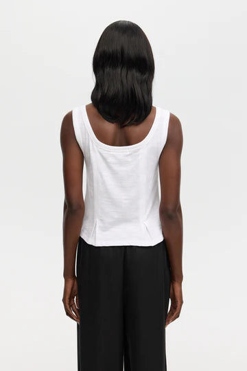 Back view of Woman wearing a white tank top with a ruffled bottom seam