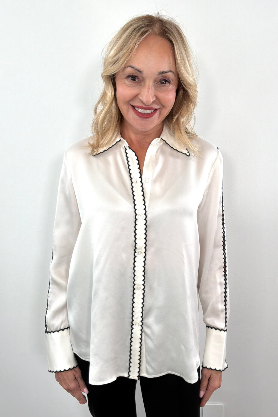 Woman wearing a white blouse with black trim 