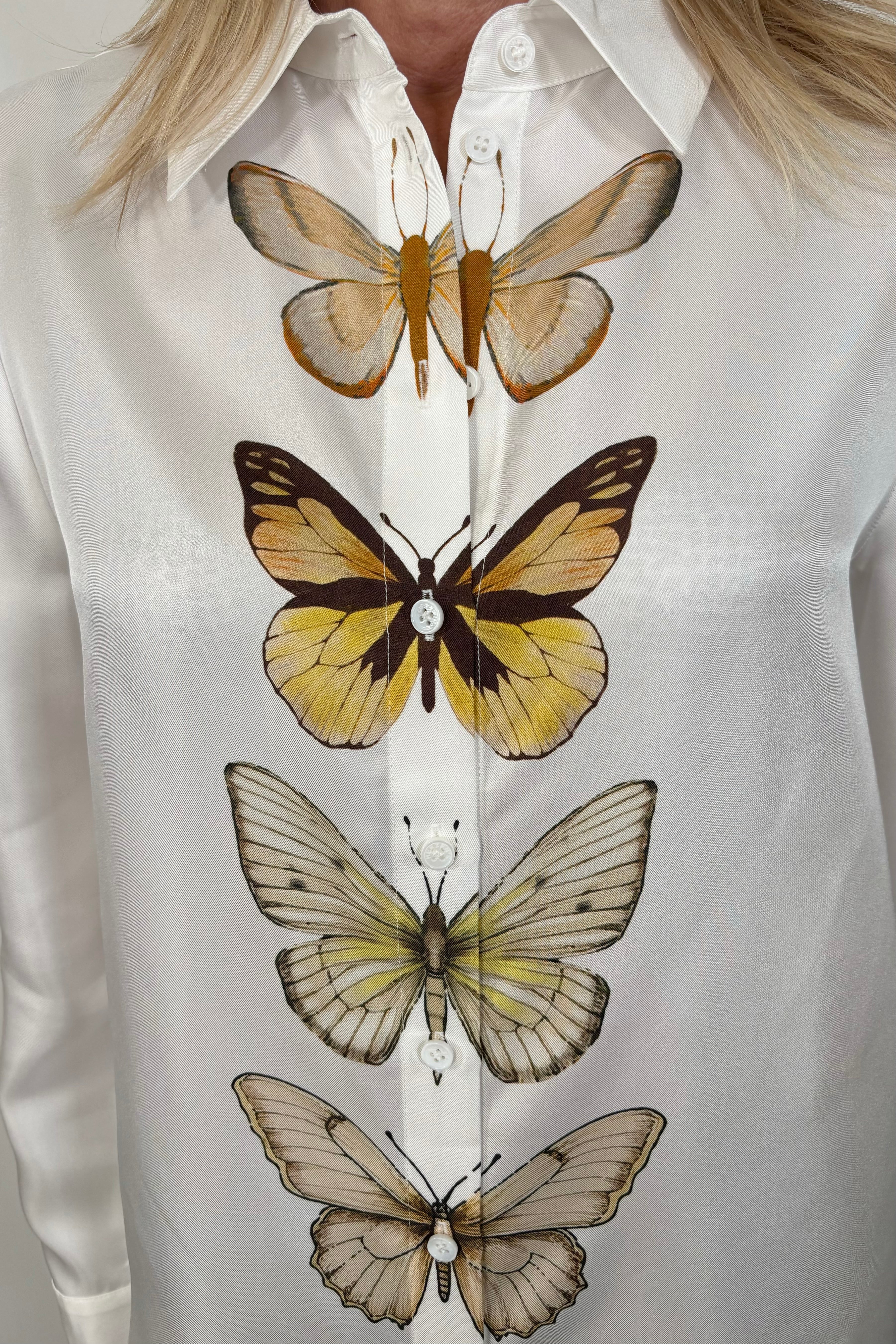 Close-up of woman wearing a butterfly patterned button up silk shirt