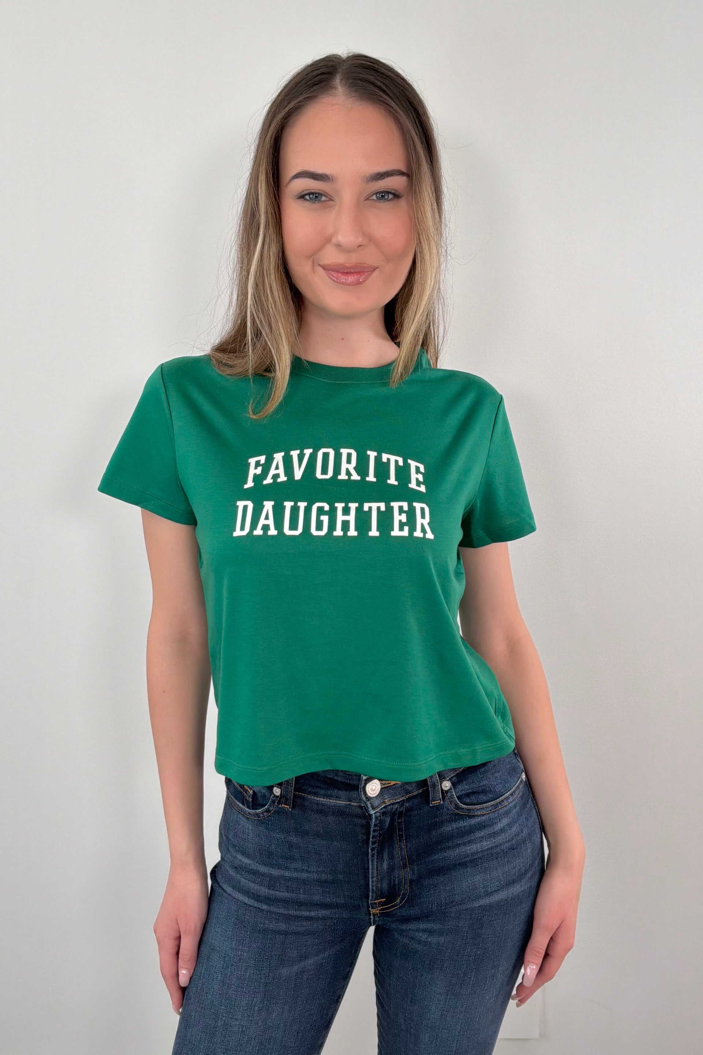 woman wearing a green t-shirt with 'FAVORITE DAUGHTER' text 