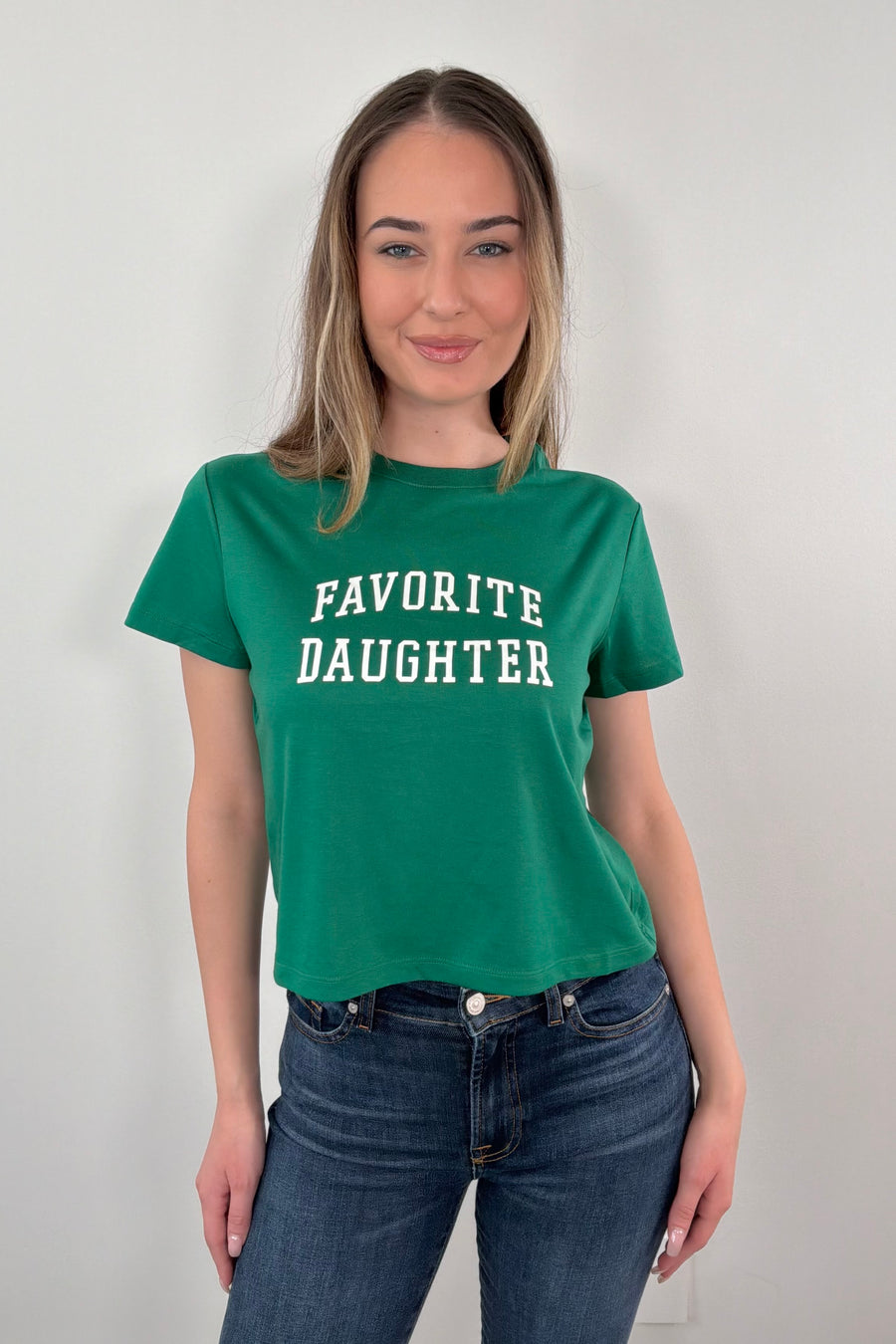 woman wearing a green t-shirt with 'FAVORITE DAUGHTER' text 