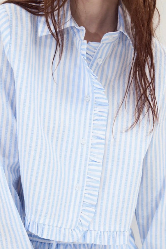 Close up of woman wearing a striped button up slept with asymmetrical button up feature