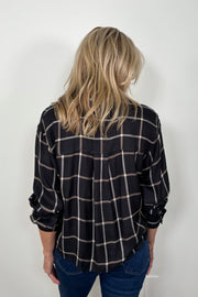 Back view of a woman wearing  a black and white plaid shirt 