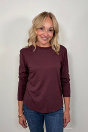 Front view of woman wearing a burgundy long sleeve crew neck tee