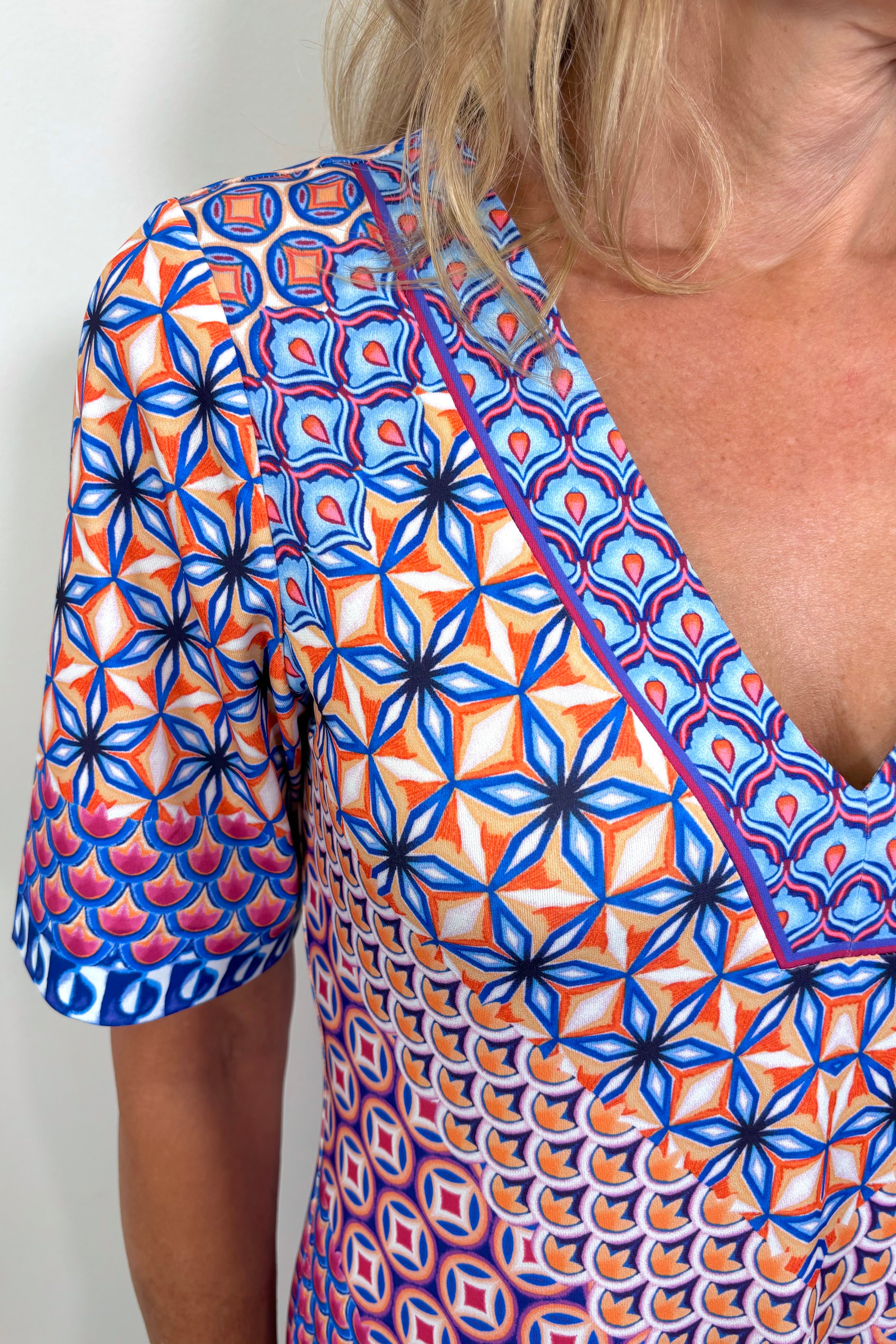 close up view of woman’s shoulder and neckline wearing a patterned jersey midi dress 