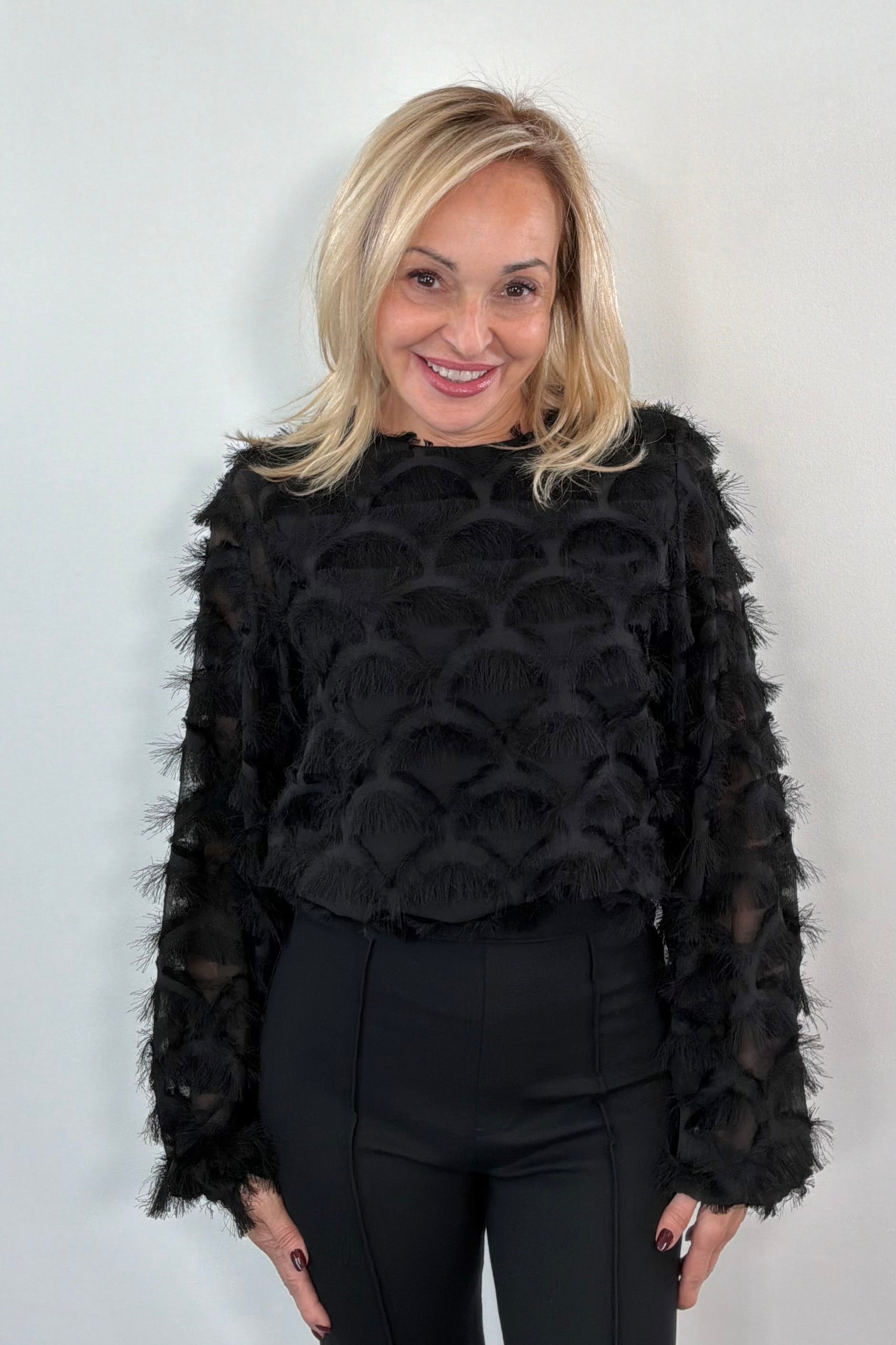 Person wearing a black top with sheer panels and frills