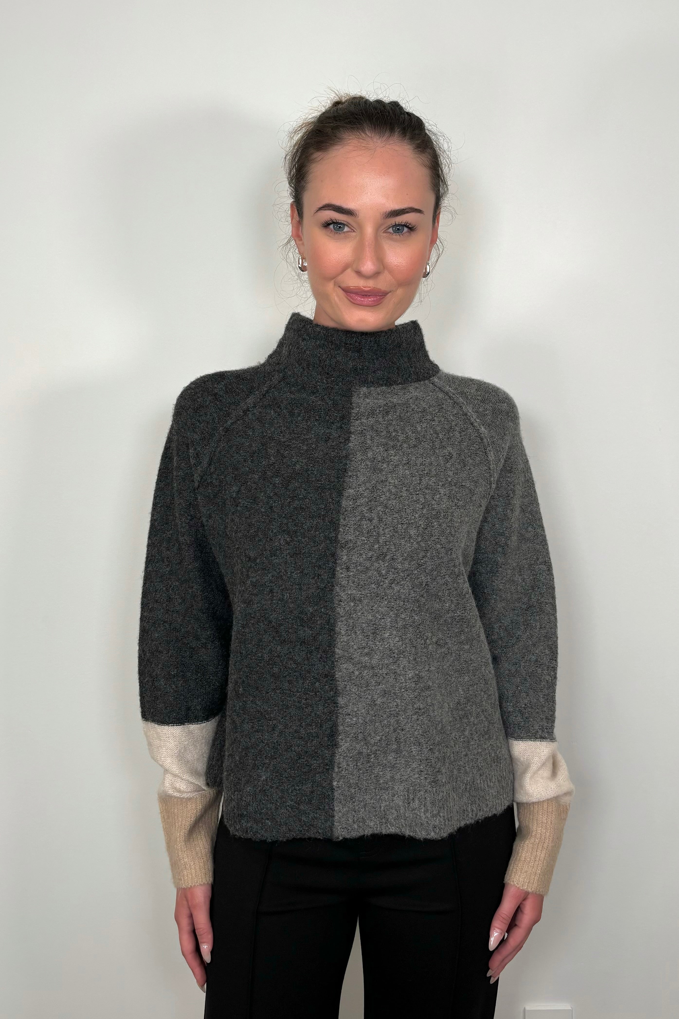 Front view of woman wearing two toned gray sweater with beige in the cuffs turtleneck sweater