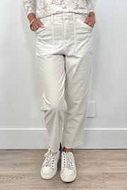Front view of a person wearing oat-coloured corduroy pants and white sneakers on a plain background