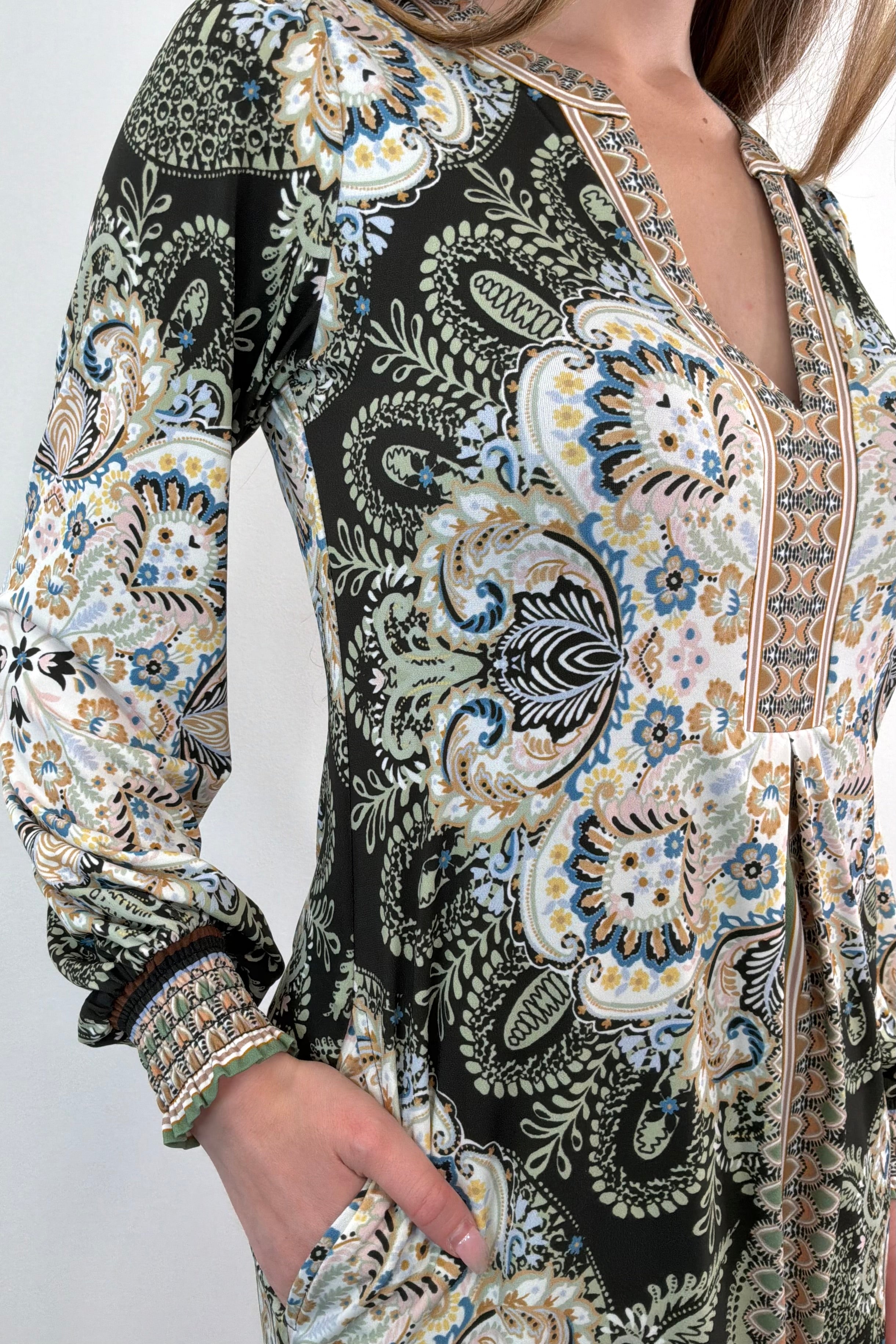 close-up of an ivory, green and black short long sleeve dress