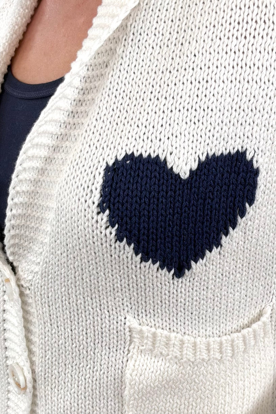 Closeup of Woman wearing white cardigan with navy detail