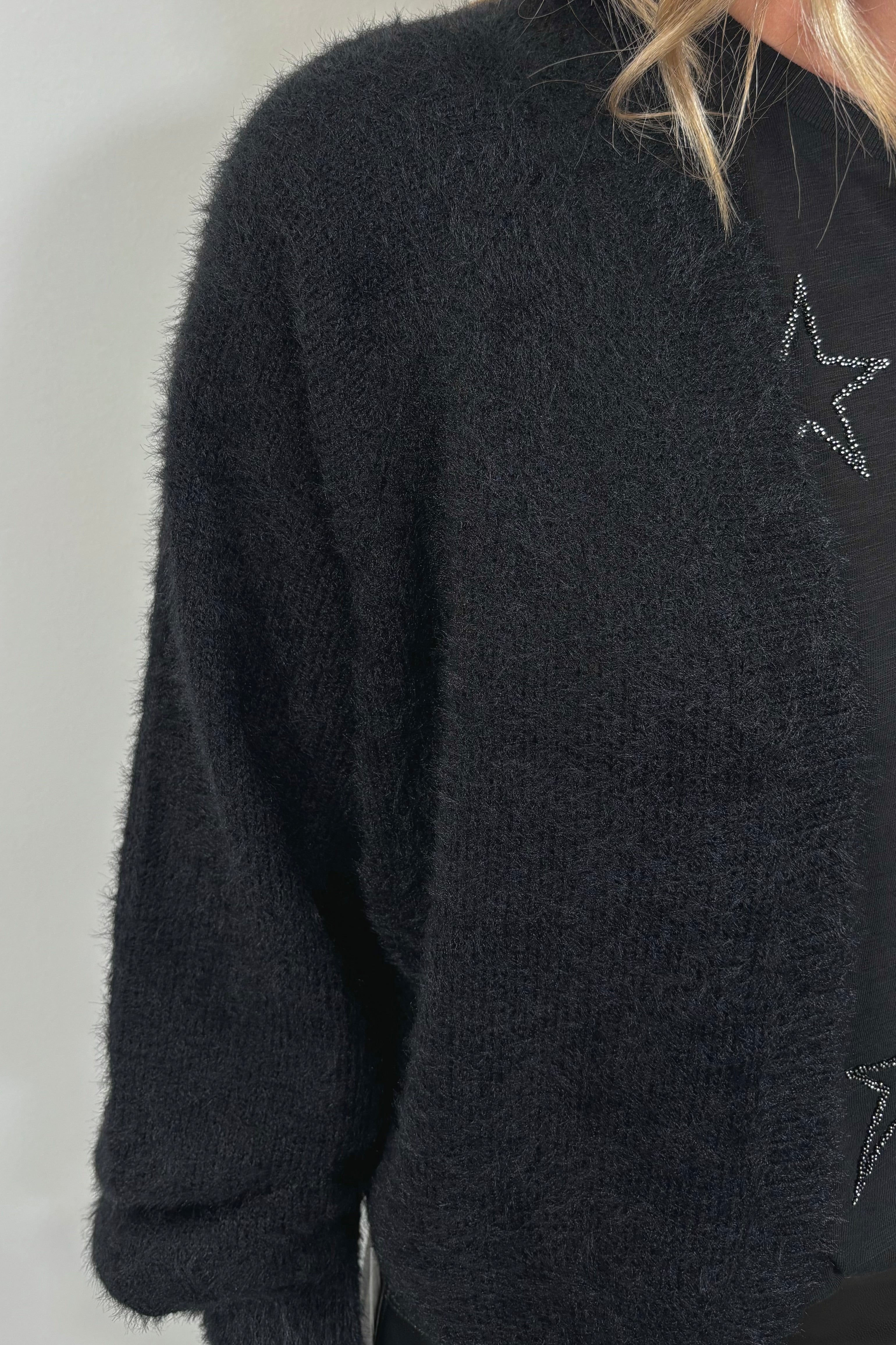 close-up of a black shrug cardigan over a star print tee