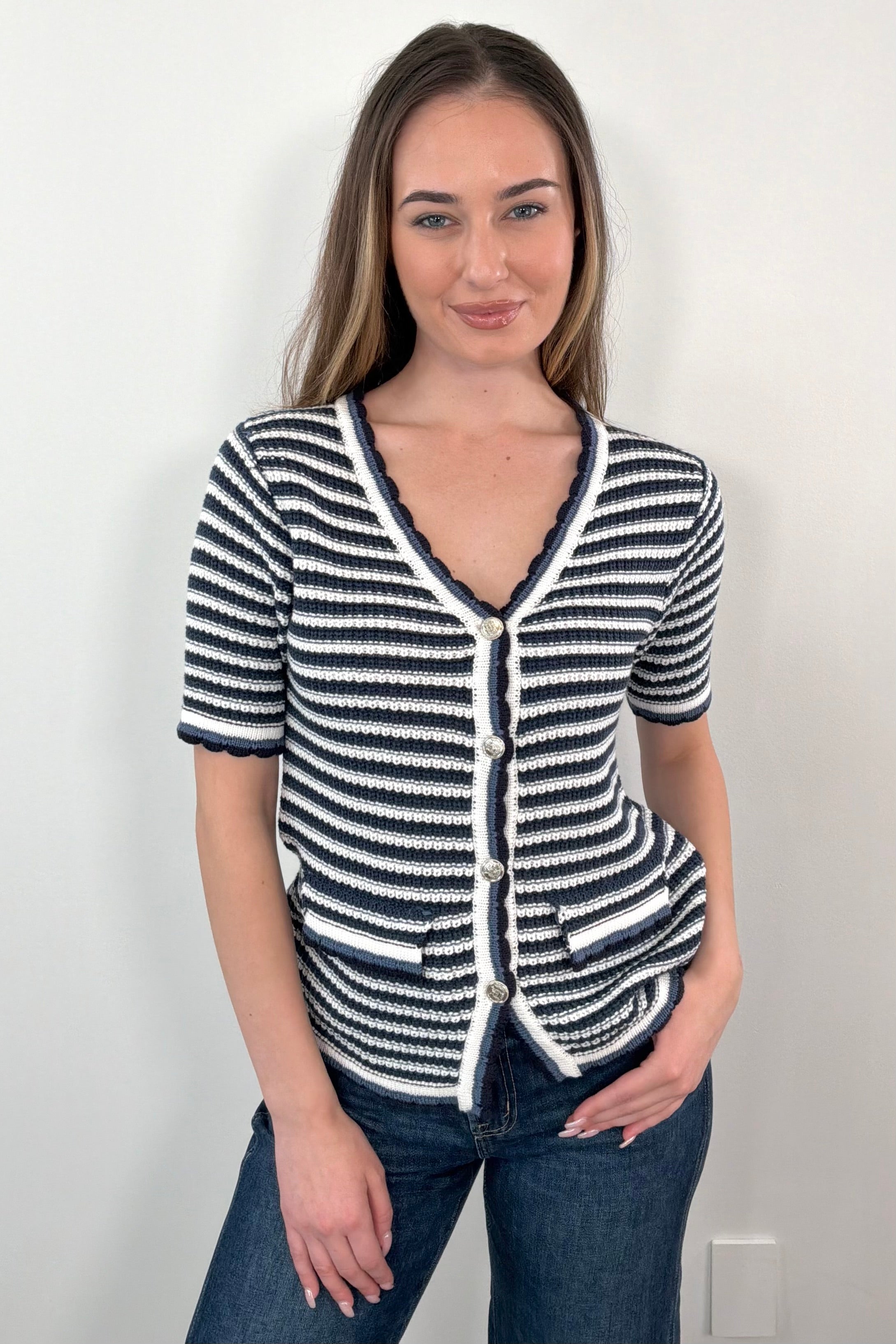 Woman wearing a navy, grey, white, black striped knit top with buttons