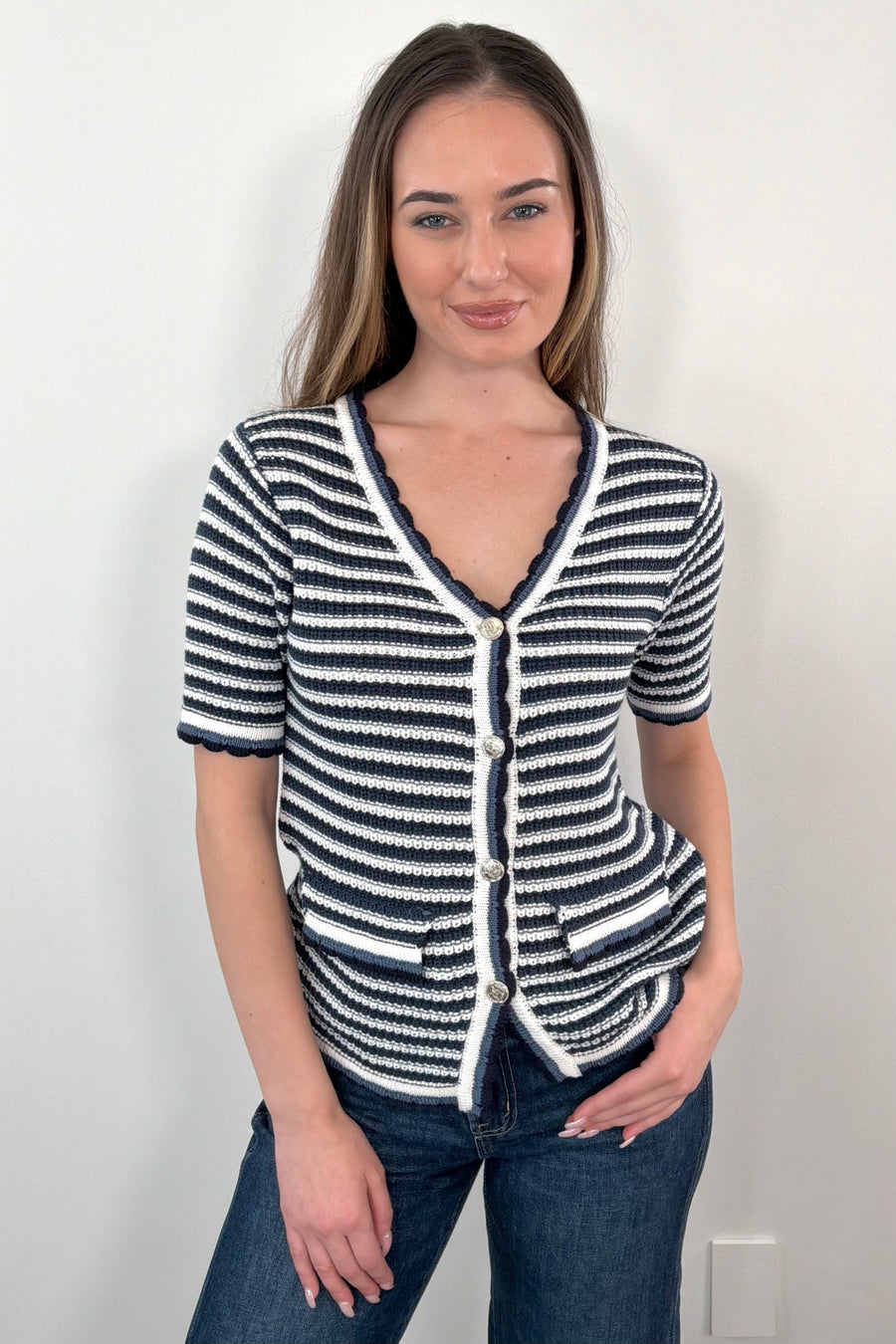 Woman wearing a navy, grey, white, black striped knit top with buttons