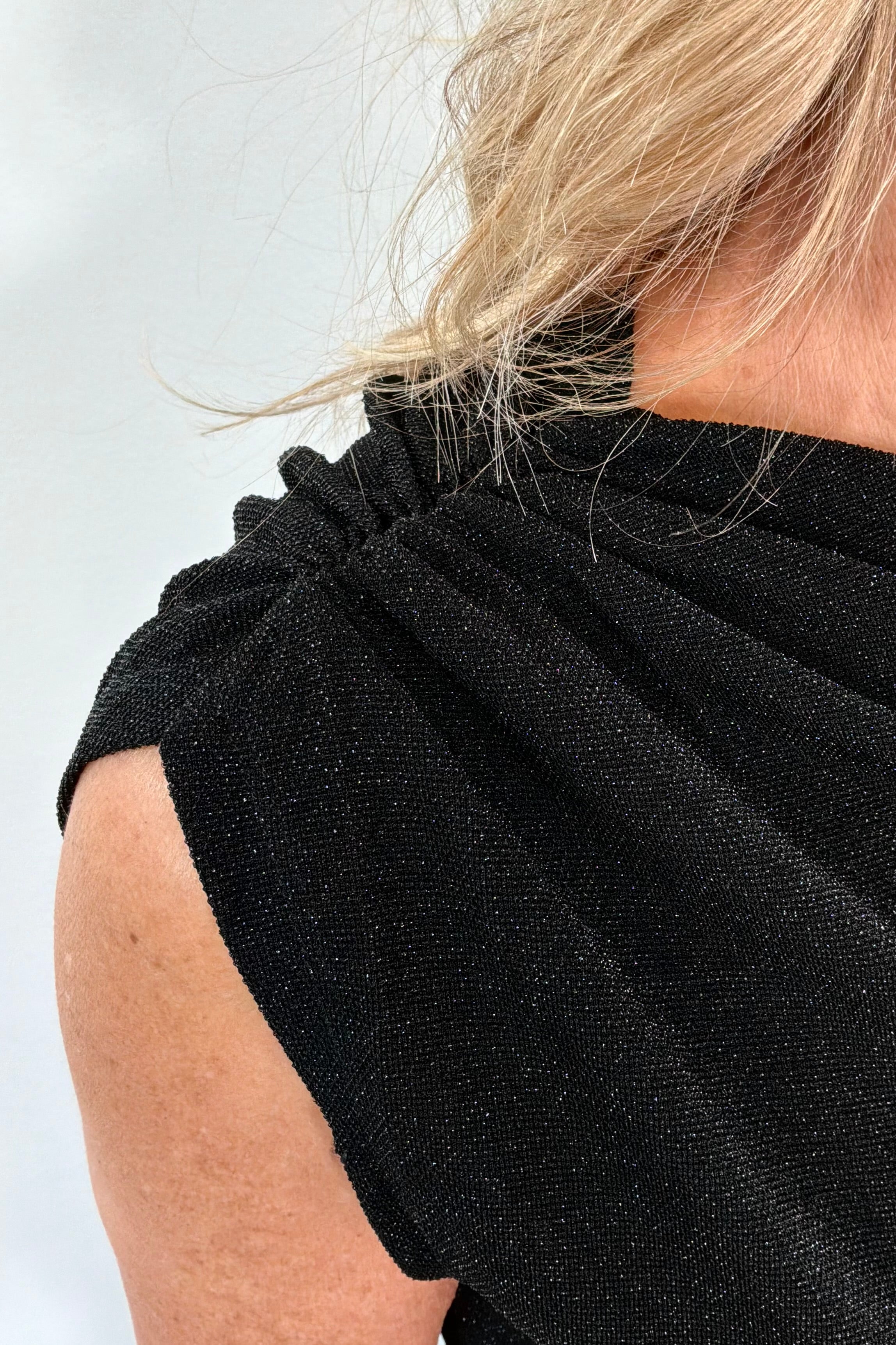 Close-up of a person wearing a black sleeveless top against a white background